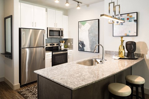 a kitchen with a marble counter top and a stainless steel refrigerator