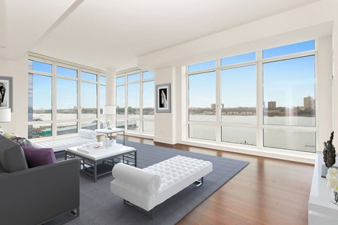 an open living room with a view of the river and a couch and a table