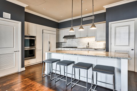 a kitchen with white cabinets and a bar with three stools