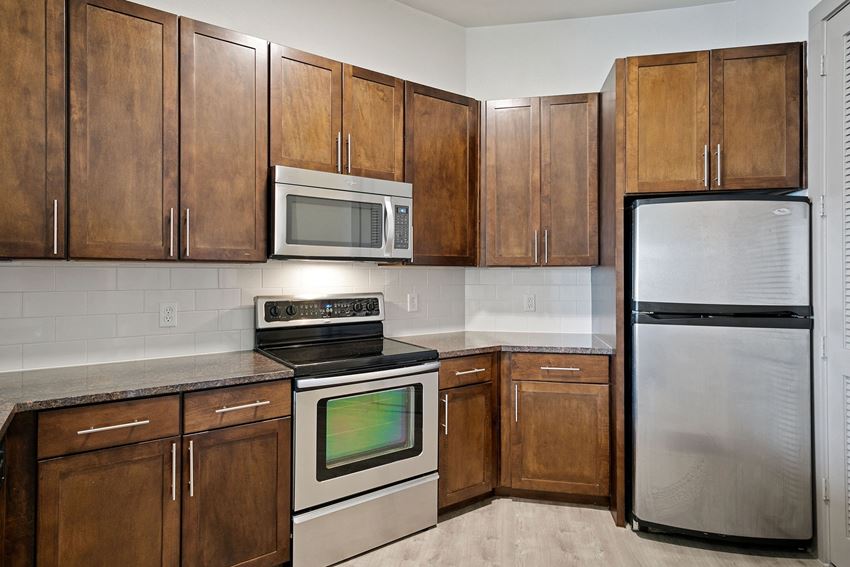 Custom cabinetry and stainless steel appliances Kitchen with wooden cabinets and appliances and a stainless steel refrigerator at The Monterey by Windsor, Dallas, Texas
