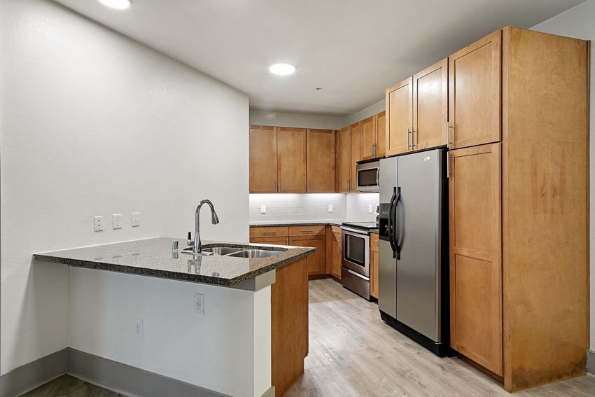 Granite island bar Kitchen with stainless steel appliances and wooden cabinets at The Monterey by Windsor, Dallas, Texas