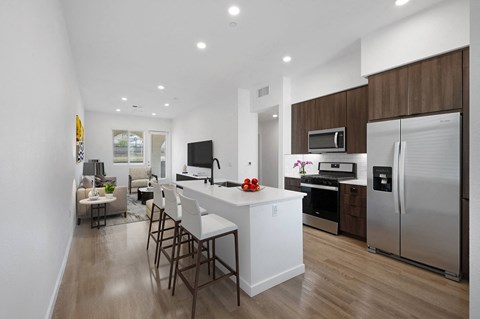 A kitchen with stainless steel appliances and a large island with chairs at Windsor Rancho PQ in San Diego, 92129