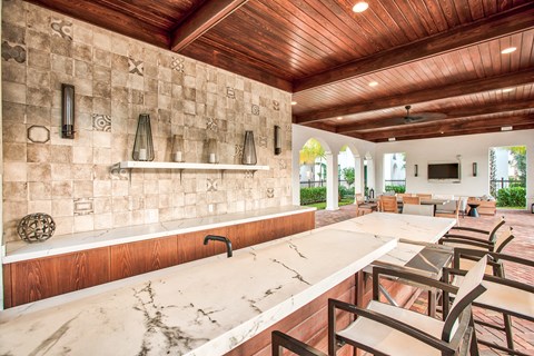 a large kitchen with marble counter tops and a bar with chairs