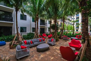 Courtyard with couches and chairs and palm trees at Windsor Ludlam Trail, an apartment complex in Miami, FL.