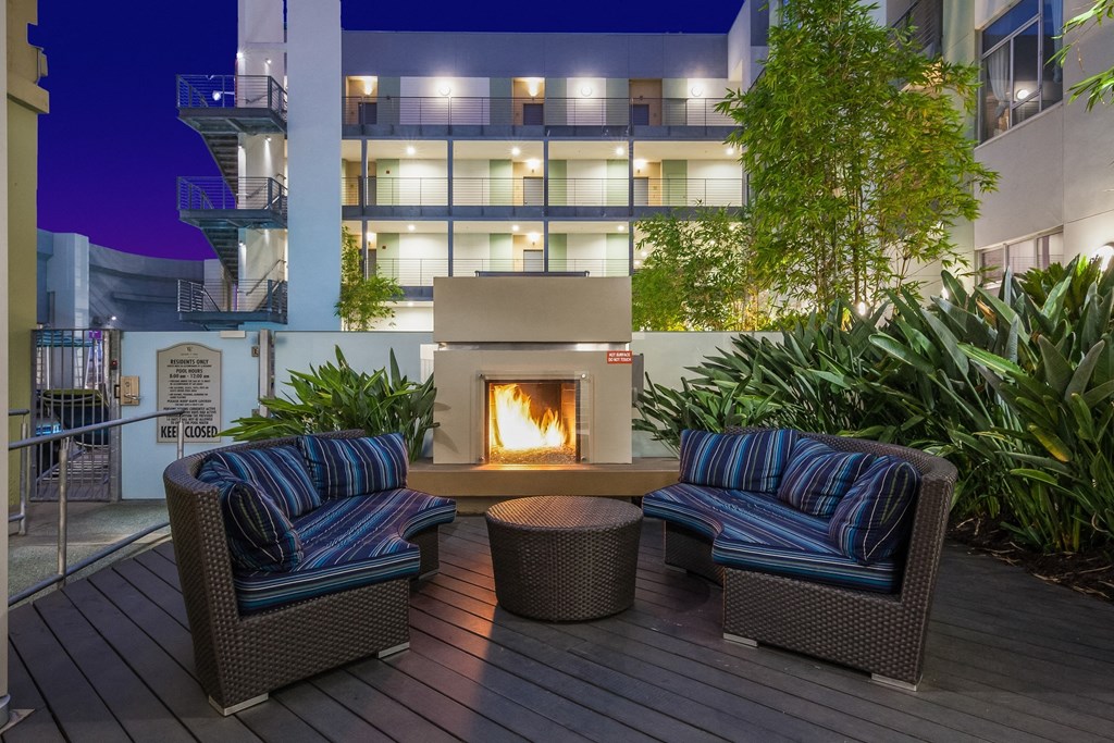 Fireplace on a patio with chairs and a table at sunset and vine