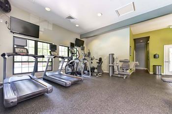 a gym with cardio equipment and a flat screen tv