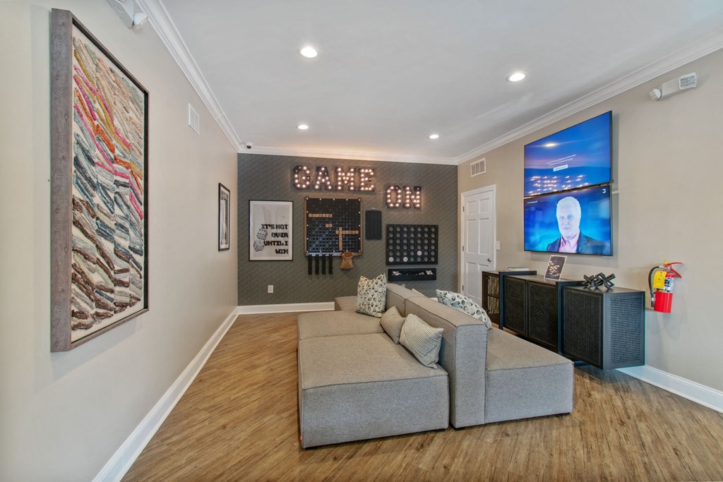 A living room with a grey sofa and a television on the wall.