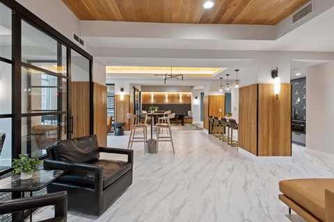 A modern living room with a black leather couch and a wooden ceiling.