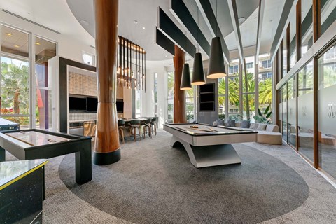 A modern living room with a pool table and a view of the outdoors.