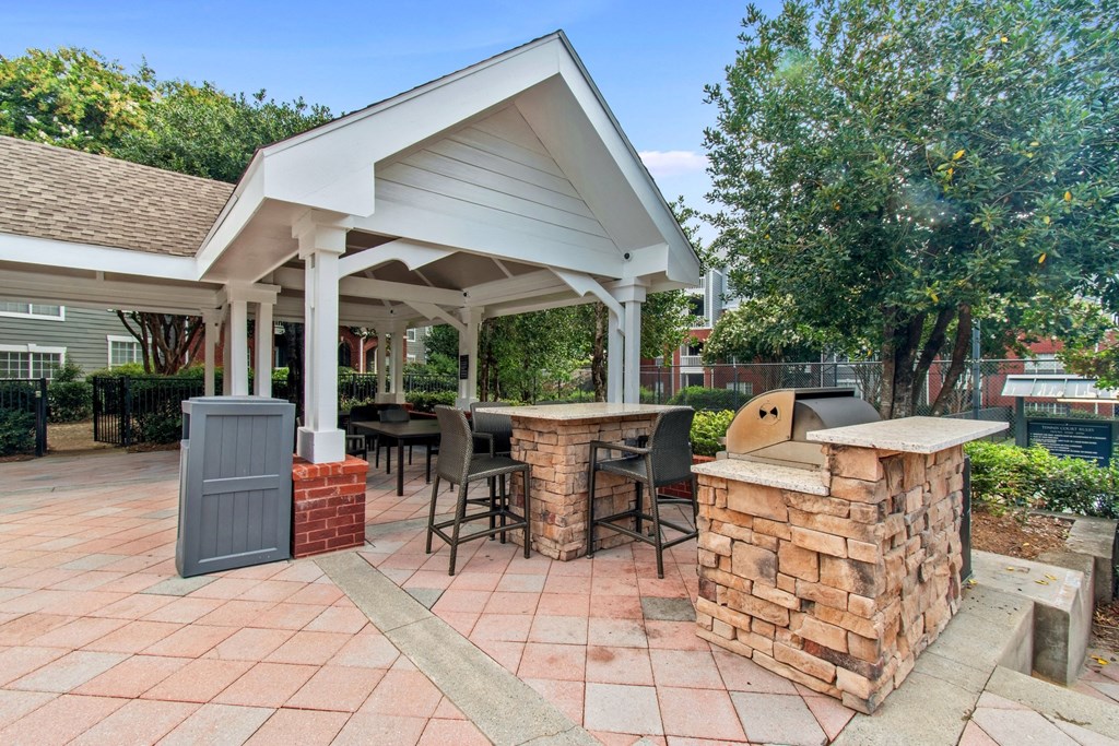 A patio with a white roofed pavilion and a brick barbecue.