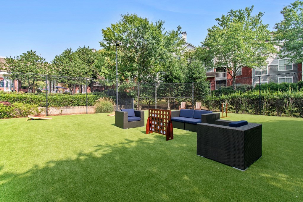 A backyard with a lawn, a black sofa, and a red chair.
