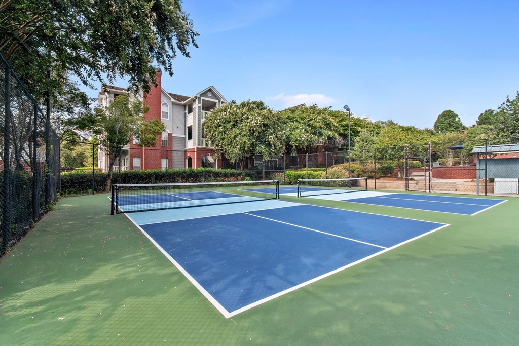 A tennis court with a red building in the background.