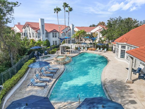 A large outdoor swimming pool surrounded by lounge chairs and umbrellas.