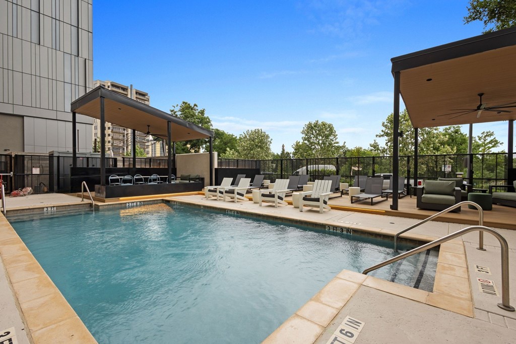 A swimming pool with a sun lounger and a black fence.