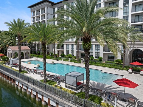 A large building with a pool and palm trees in front.