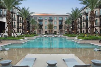 a swimming pool with palm trees in front of an apartment building at The Sterling at Regent Square, Houston, 77019