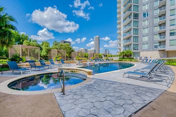 a resort style pool with chaise lounge chairs and a city skyline in the background