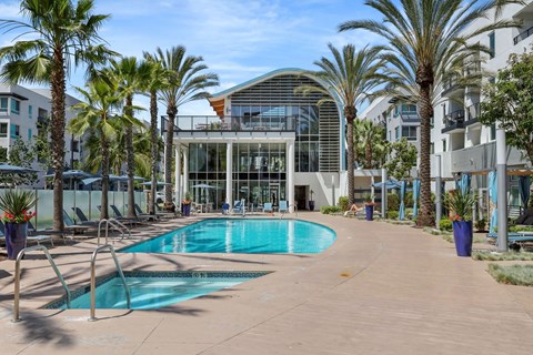 A pool surrounded by palm trees and a building in the background.