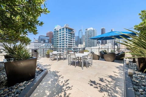 A rooftop patio with tables and chairs overlooking a city skyline.