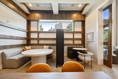 A modern dining room with a round table and orange chairs.