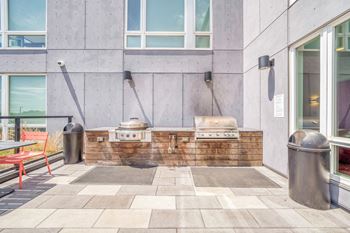 an outdoor kitchen with two bbq grills and two trash cans