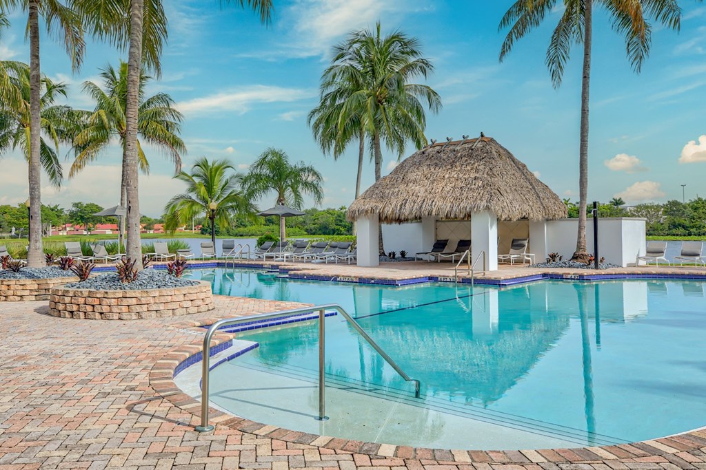 a resort style pool with a tiki hut in the background