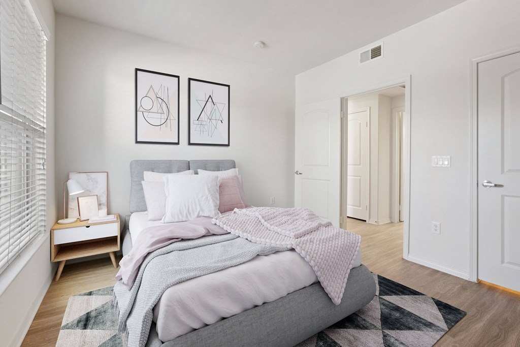 a bedroom with white walls and a gray bed
