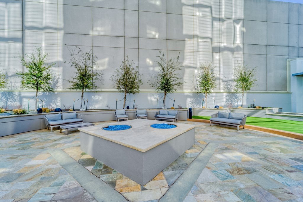 a large lobby with seating and a fountain with trees in the background