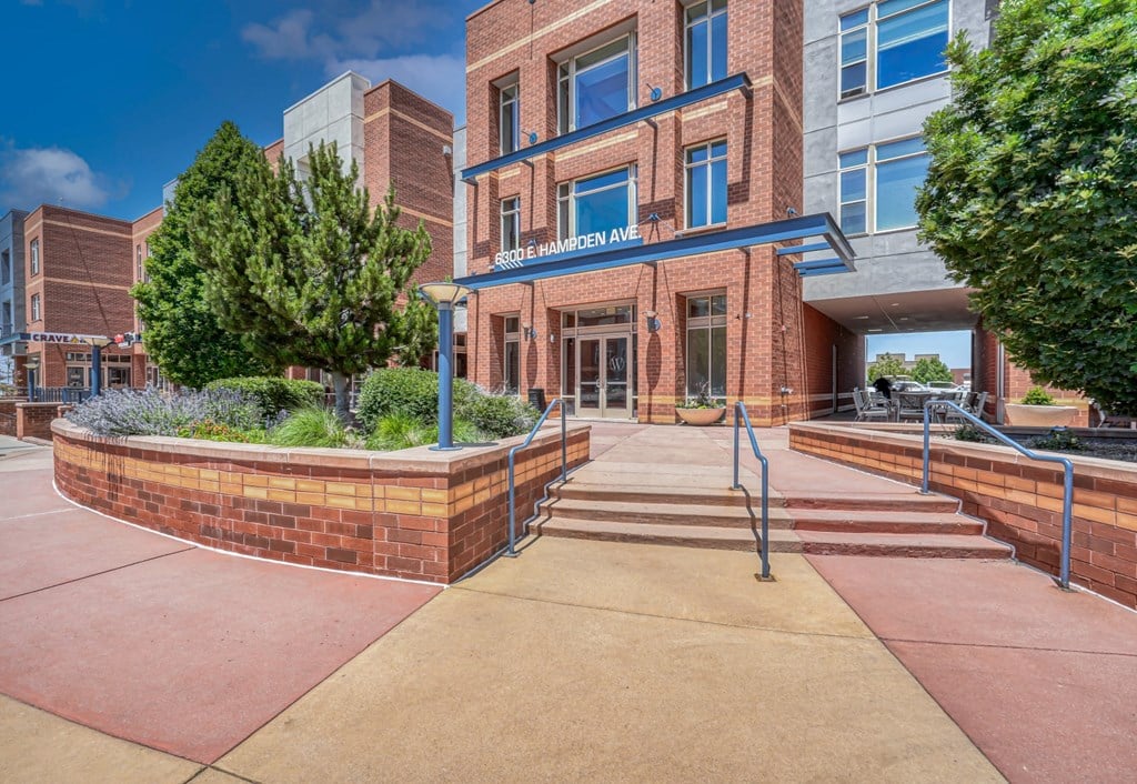 A brick building with a blue awning and stairs in front of it at The District, Denver, CO
