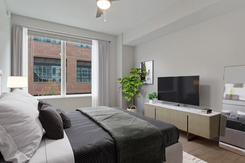 a bedroom with a large window and a bed and a tv