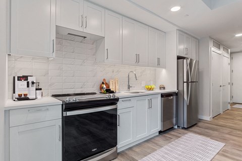 a white kitchen with stainless steel appliances and white cabinets