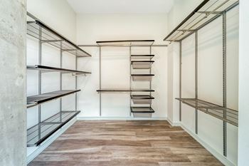 a spacious walk in closet with white walls and hardwood floors