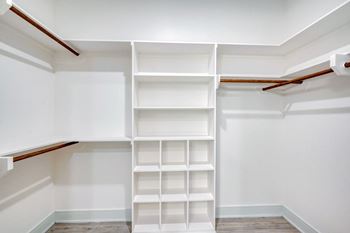 a walk in closet with white shelves and white walls