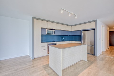 a kitchen with a large island and a stainless steel refrigerator