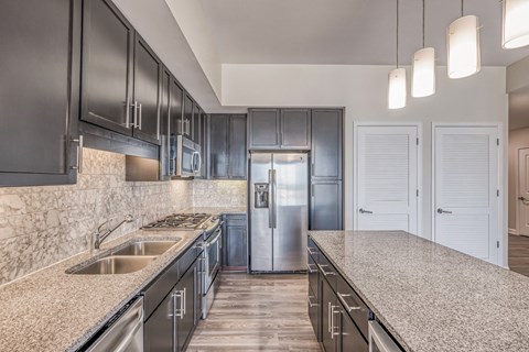 a kitchen with granite counter tops and a stainless steel refrigerator