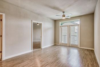 an empty living room with a ceiling fan