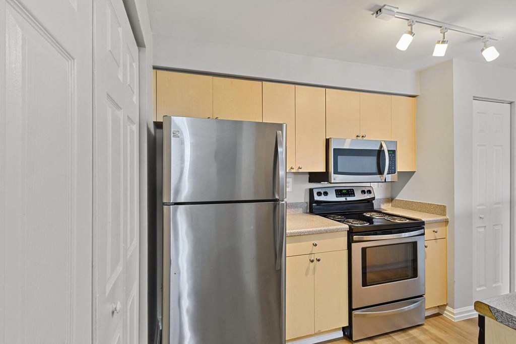 A kitchen with wooden cabinets and stainless steel appliances at The Winston by Windsor, Pembroke Pines, Florida