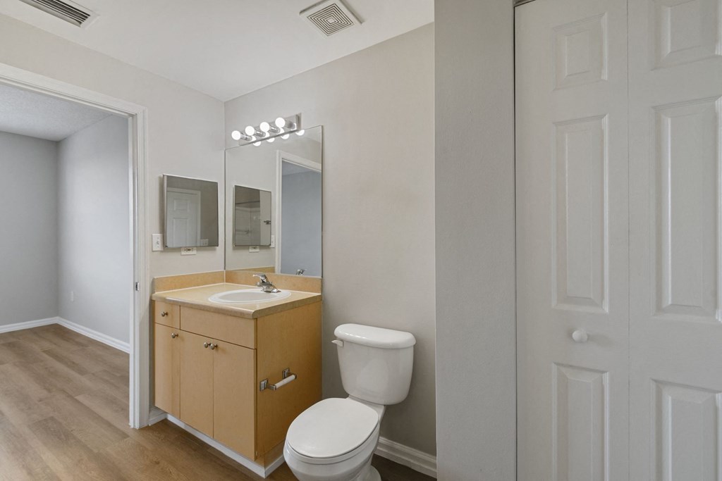 A bathroom with a toilet sink and mirror at The Winston by Windsor, Pembroke Pines, Florida