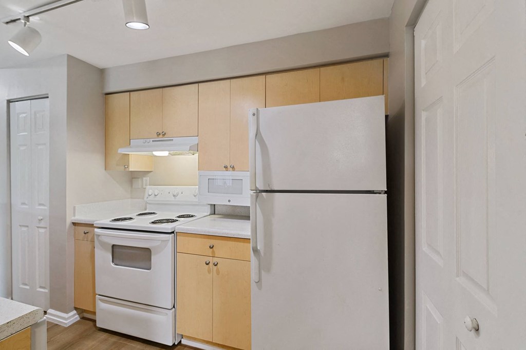 A kitchen with white appliances and wooden cabinets at The Winston by Windsor, Pembroke Pines, Florida