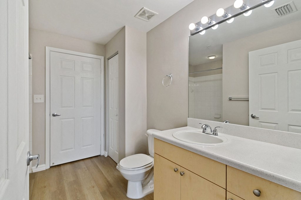 A bathroom with a toilet sink and mirror at The Winston by Windsor, Pembroke Pines, Florida