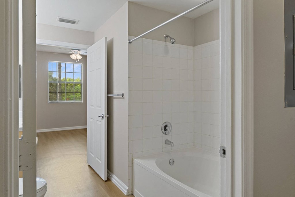 A bathroom with a white tub and a white door at The Winston by Windsor, Pembroke Pines, Florida