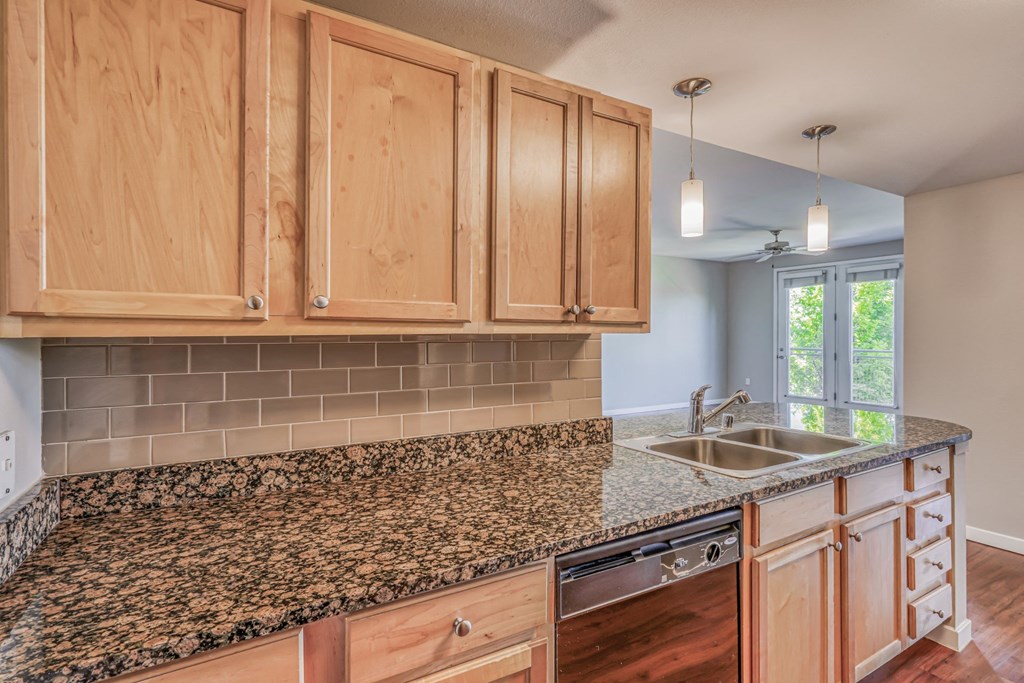 A kitchen with granite countertops and wood cabinets at The District, Denver, CO