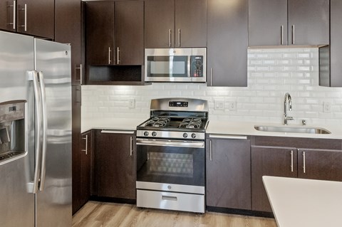 A modern kitchen with a stainless steel refrigerator and oven.