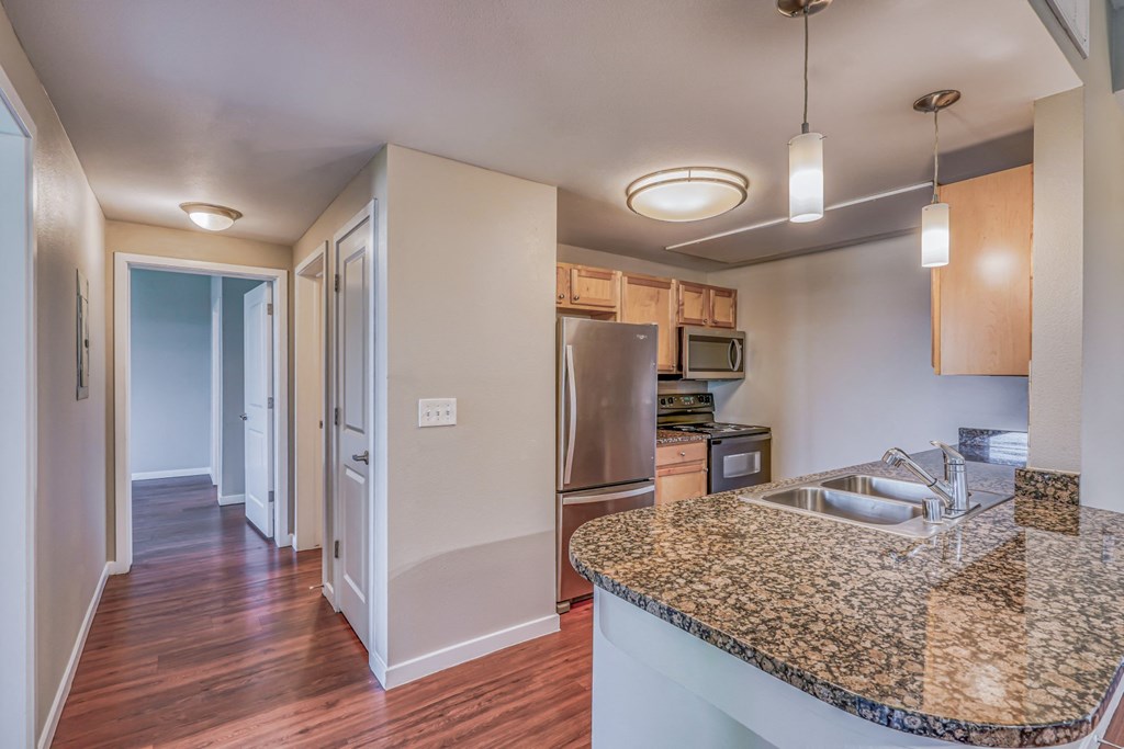 A kitchen with granite countertops and stainless steel appliances at The District, Denver, CO