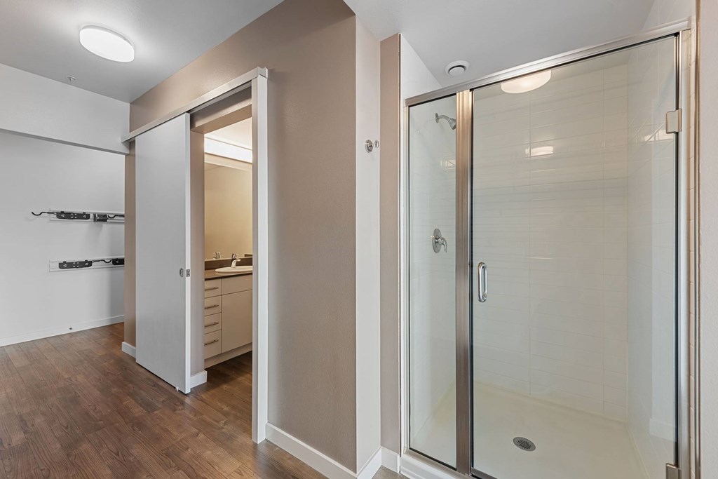 A bathroom with a walk-in shower and a doorway leading to a kitchen.