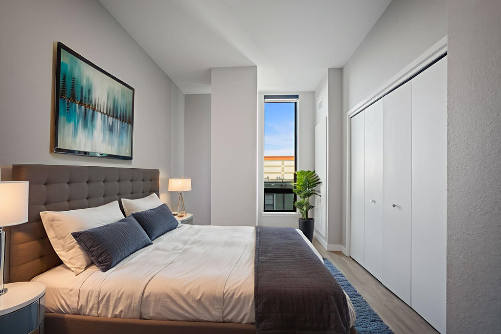 A bedroom with a large bed and a painting on the wall.