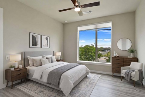 A bedroom with a large bed, a window with a view, and a ceiling fan.