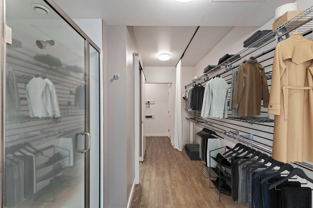 A walk in closet with clothes hanging on shelves and a mirror.