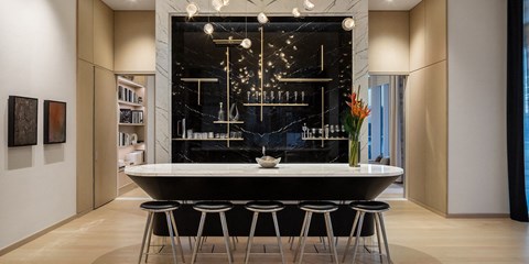 a kitchen with a large black counter and bar stools