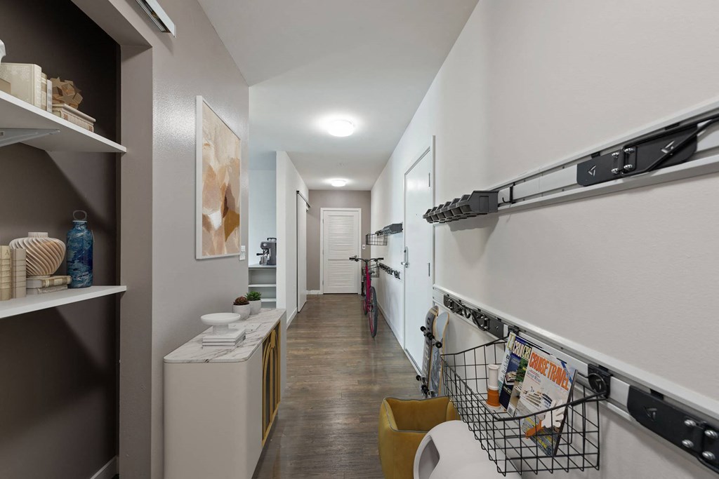 A hallway with a white door, a white cabinet, and a black rack on the wall.
